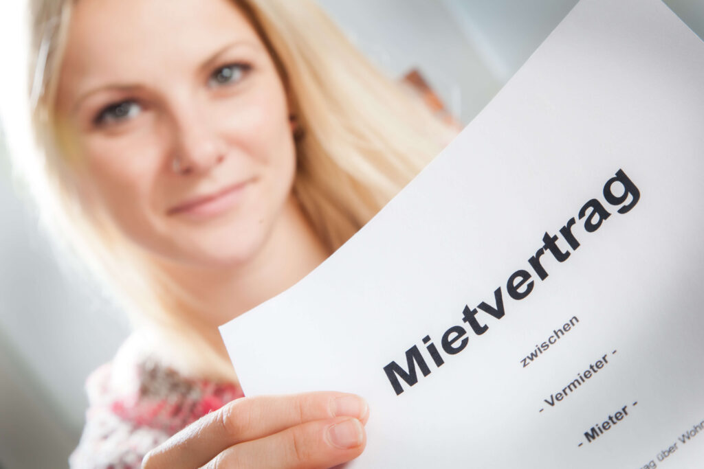 Eine Frau präsentiert ein Dokument mit der Aufschrift „Mietvertrag“.